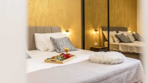 Hotellihuone, jossa on sänky, yöpöytä ja peili.
