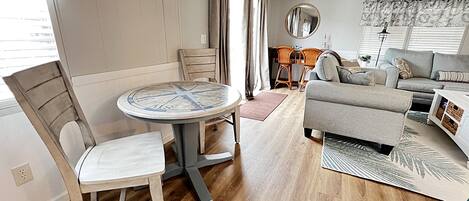 A living room with a round table, a sofa, and a dining area with chairs.
