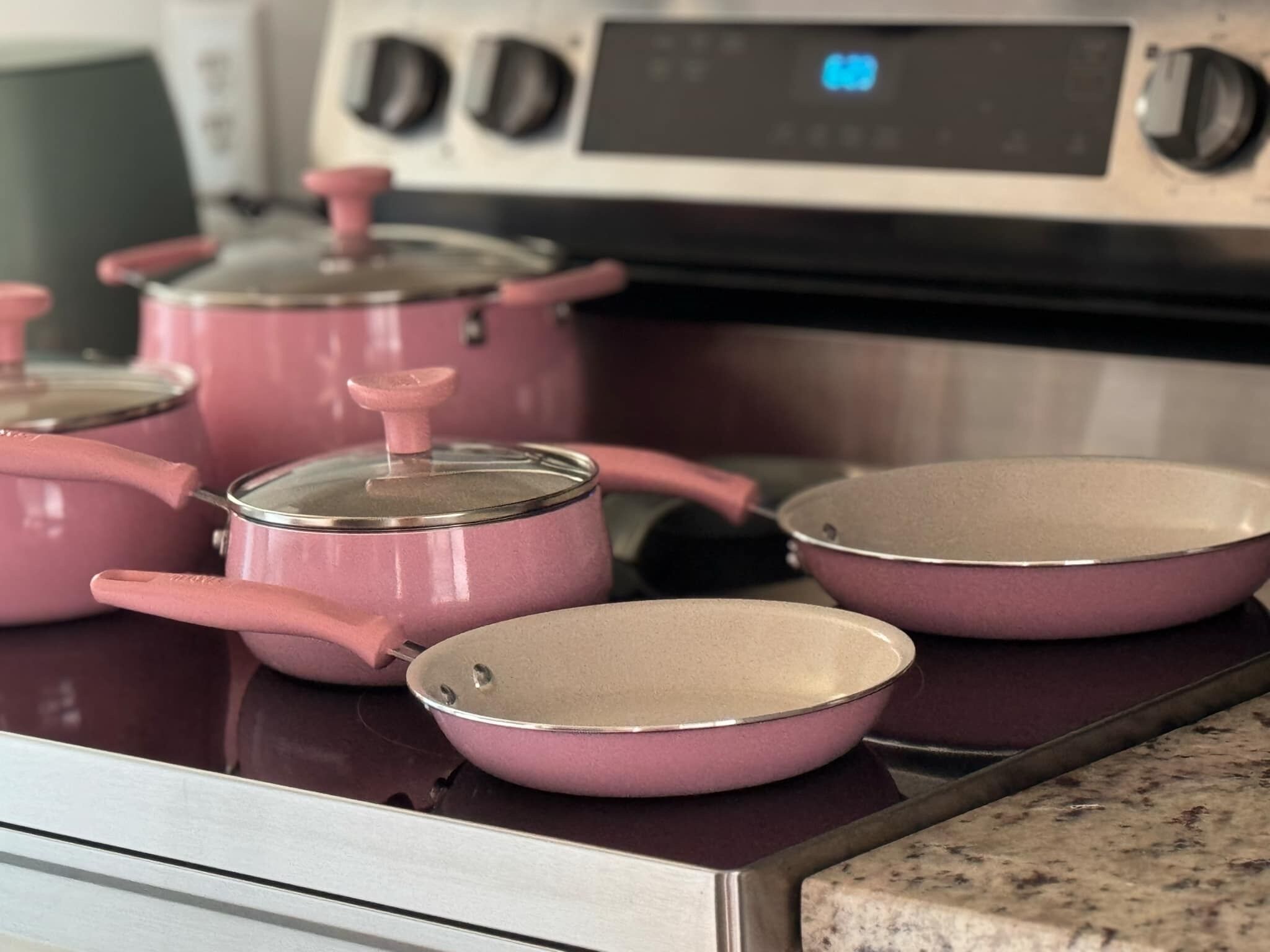 A kitchen with pink cookware on a stove.