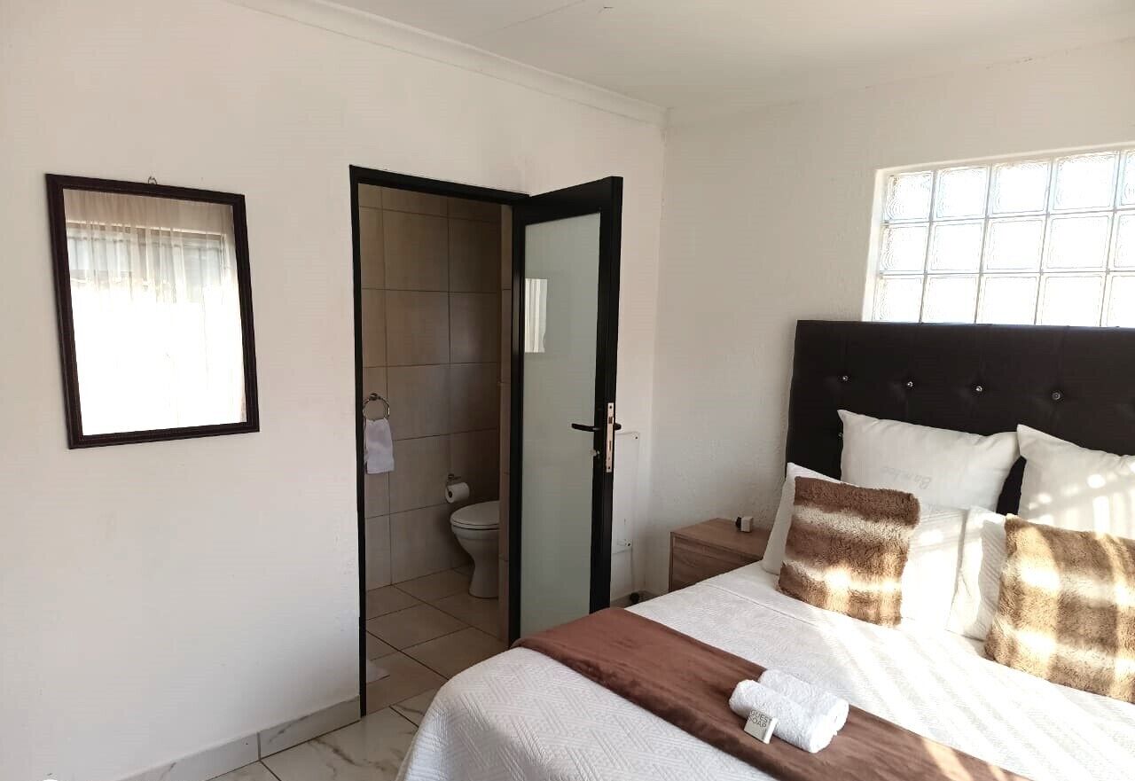 Une chambre à coucher avec un lit, une table de chevet, une fenêtre et une porte menant à la salle de bain.