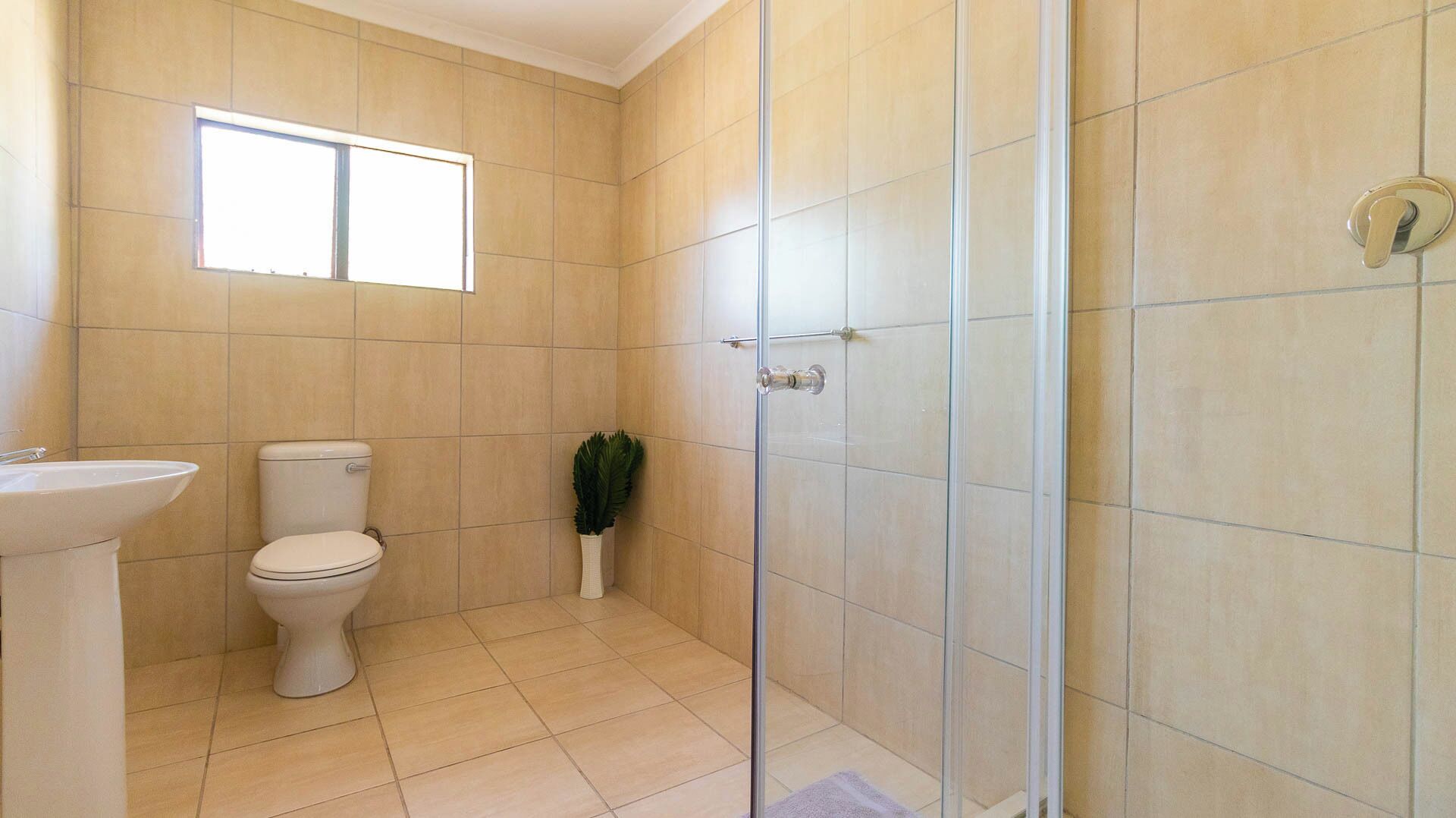 A bathroom with a toilet, sink, and glass shower door.