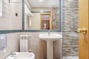 A bathroom with a sink, toilet, and shower area. - Hostal Don Juan  (Meco)