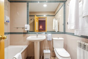 A bathroom with a sink, toilet, and bathtub. - Hostal Don Juan  (Meco)