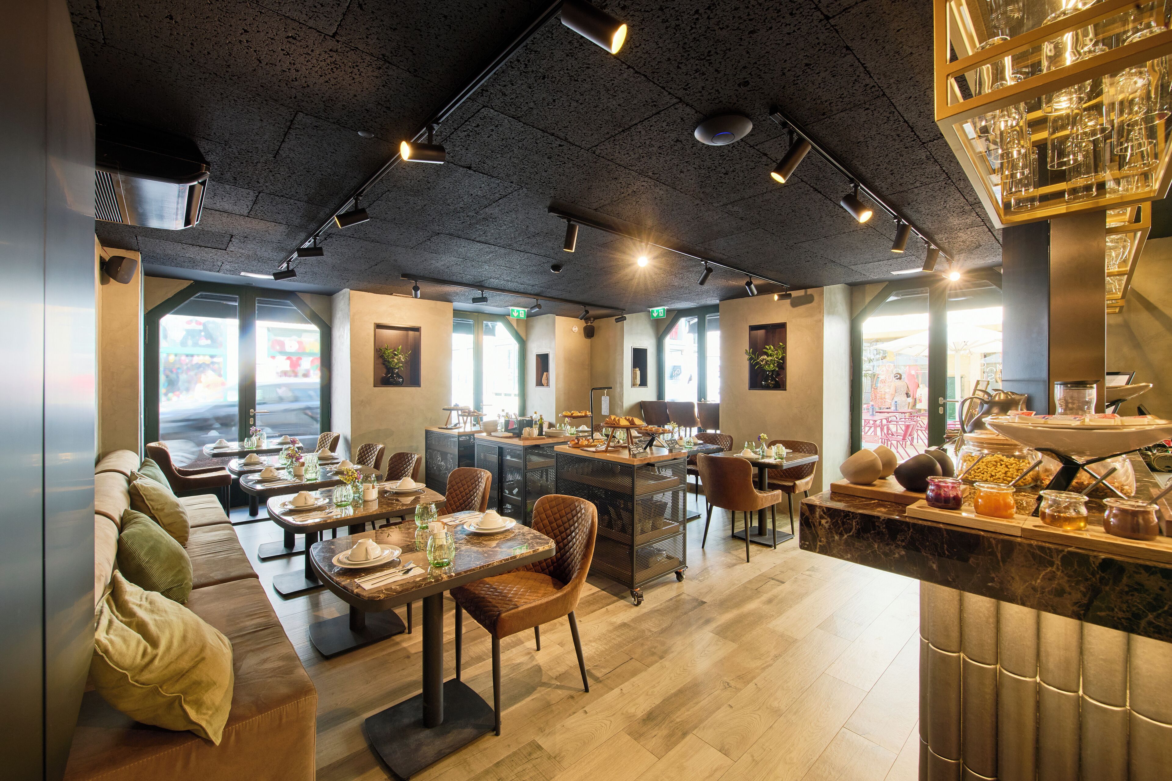 A restaurant with a long counter, seating area with couches and chairs, and a buffet with various food items.