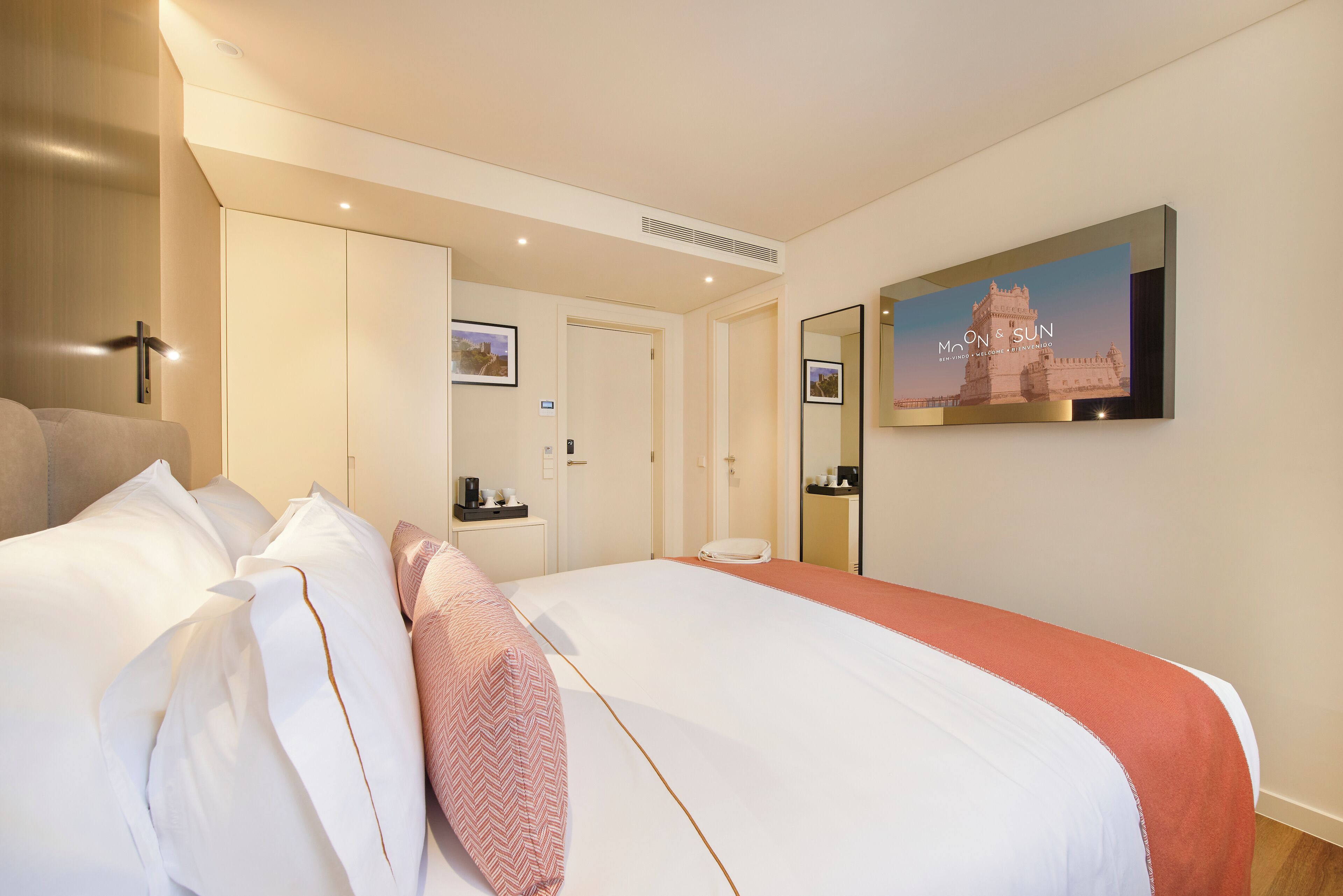A hotel room with a large bed, a flat-screen TV mounted on the wall, and a framed picture of a building.