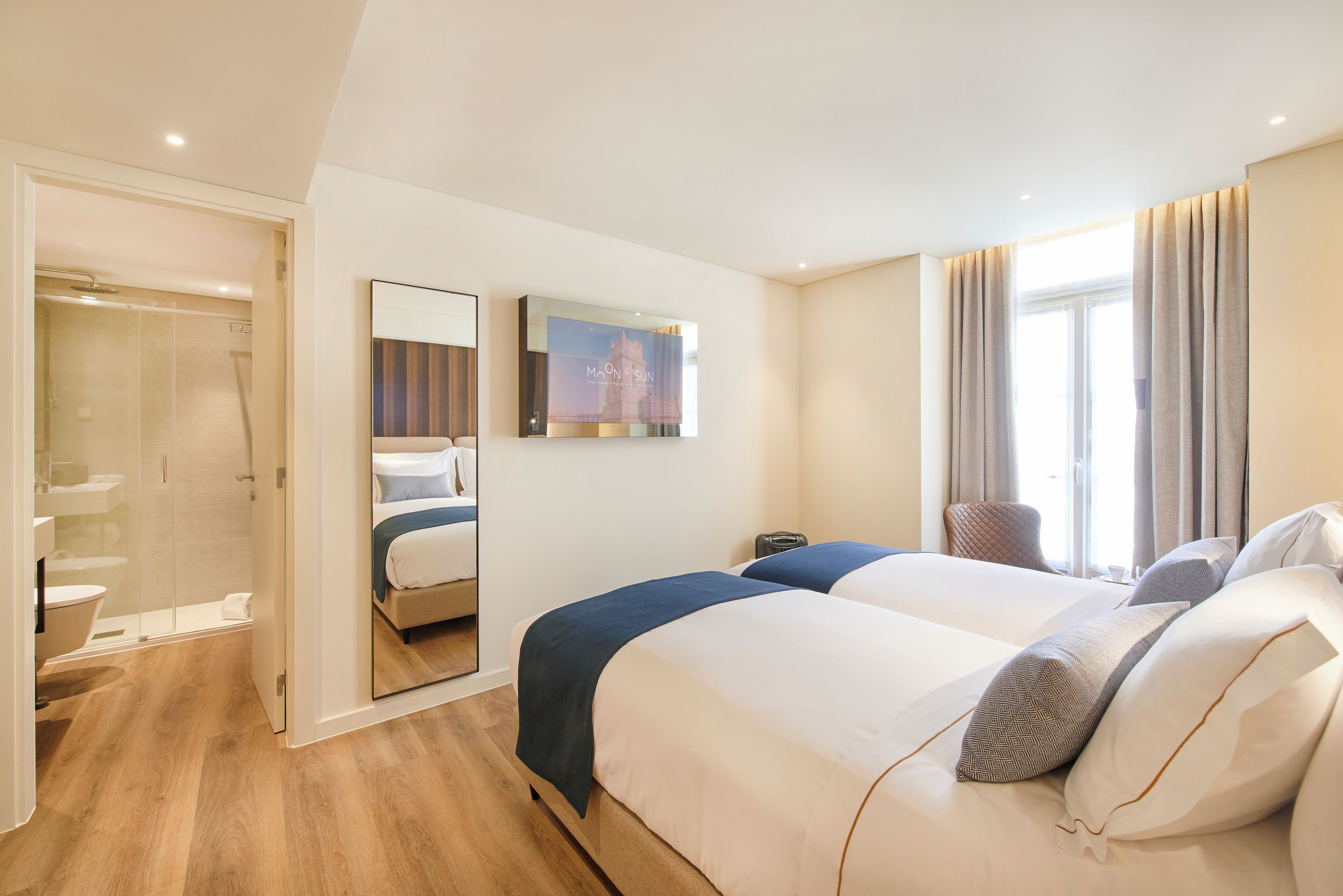 Ein Hotelzimmer mit einem großen Bett, einer Dusche, einem Badezimmer und einem großen Fenster mit Vorhängen.