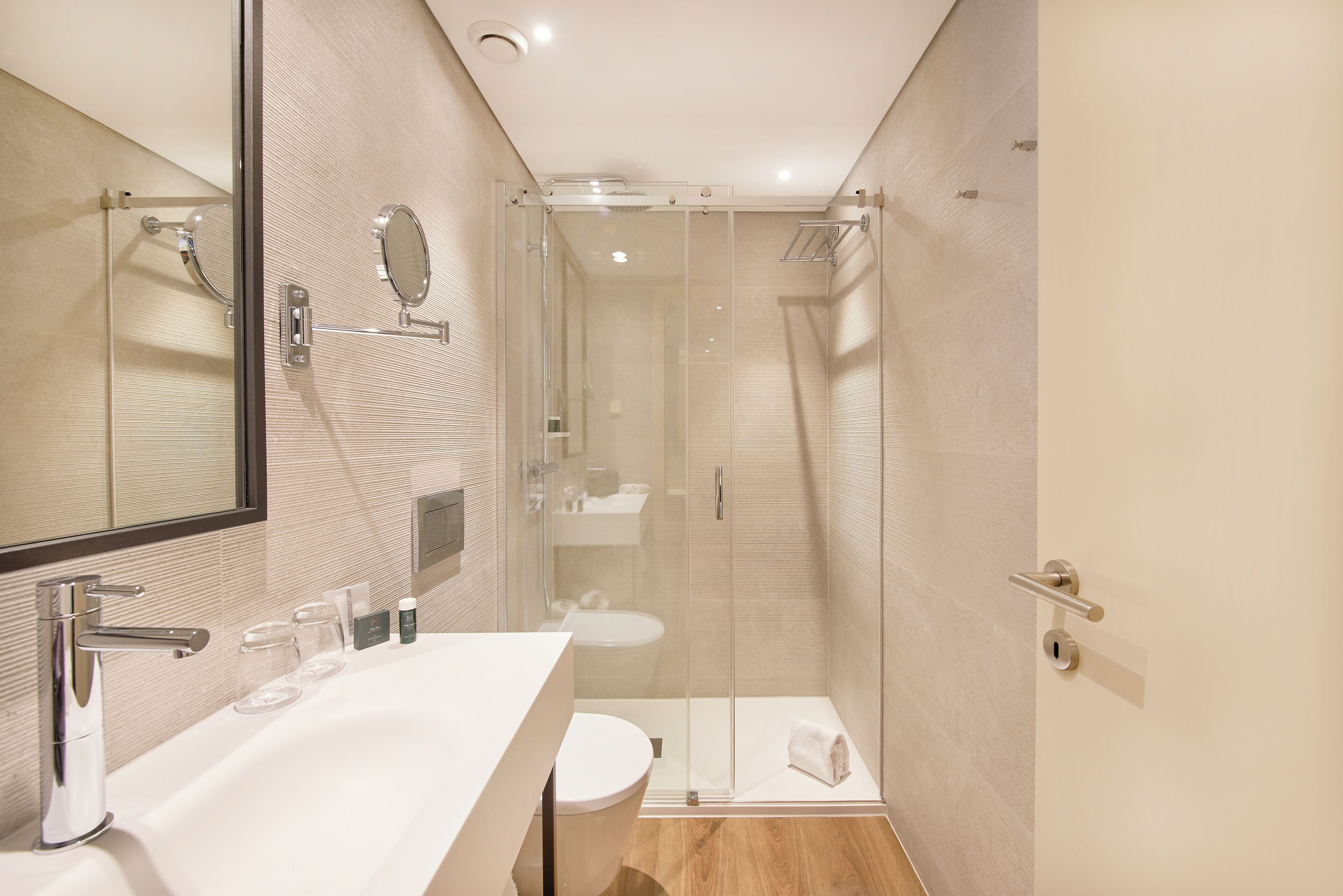 A modern bathroom with a glass-enclosed shower, a white sink, and a large mirror.