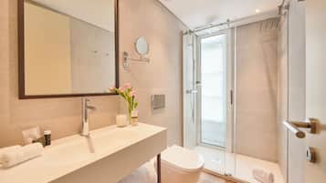 A modern bathroom with a large mirror, a sink, a toilet, and a shower area.