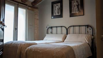Een slaapkamer met een tweepersoonsbed, stenen muren en twee ingelijste kunstwerken aan de wand.
