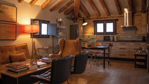 A cozy living room with a sofa, a coffee table, and a fireplace. There is a kitchen area with a stove, sink, and cabinets.