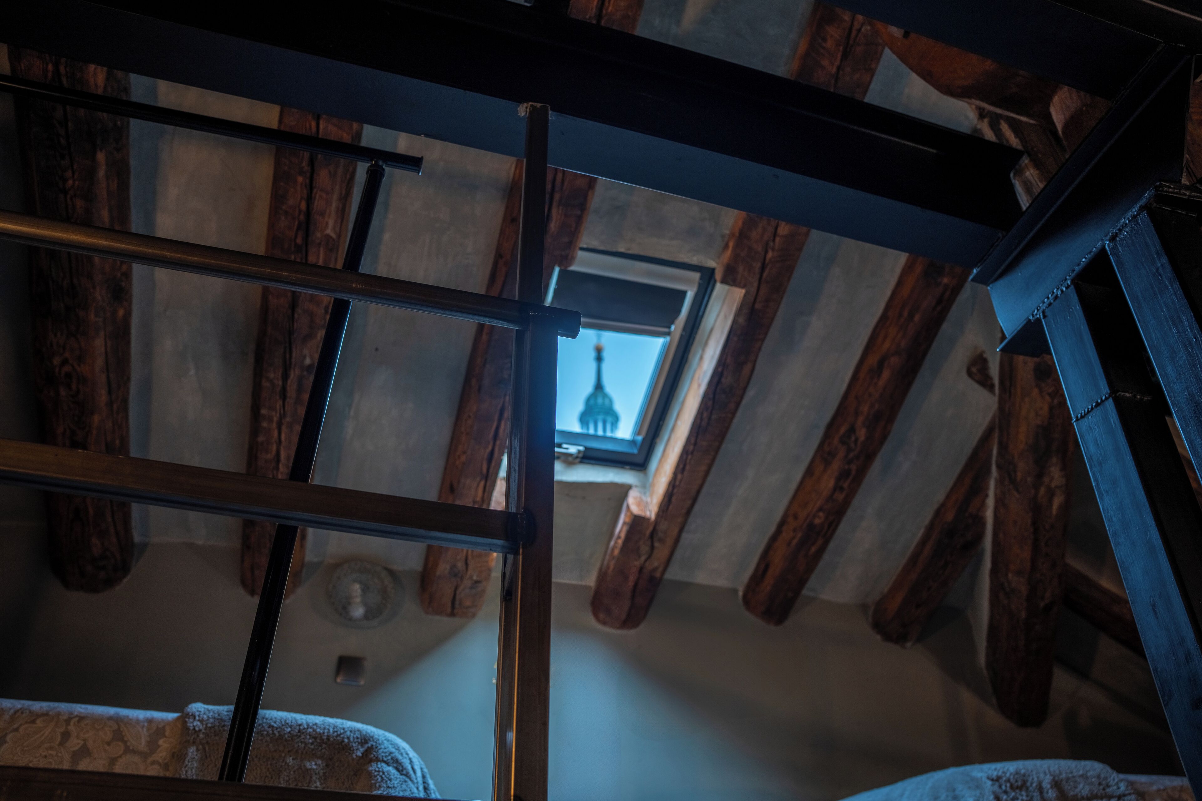 Una habitación con vigas de madera a la vista y tragaluces.