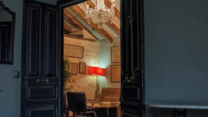 A room with a bed, a desk, a chair, a lamp, and a chandelier.