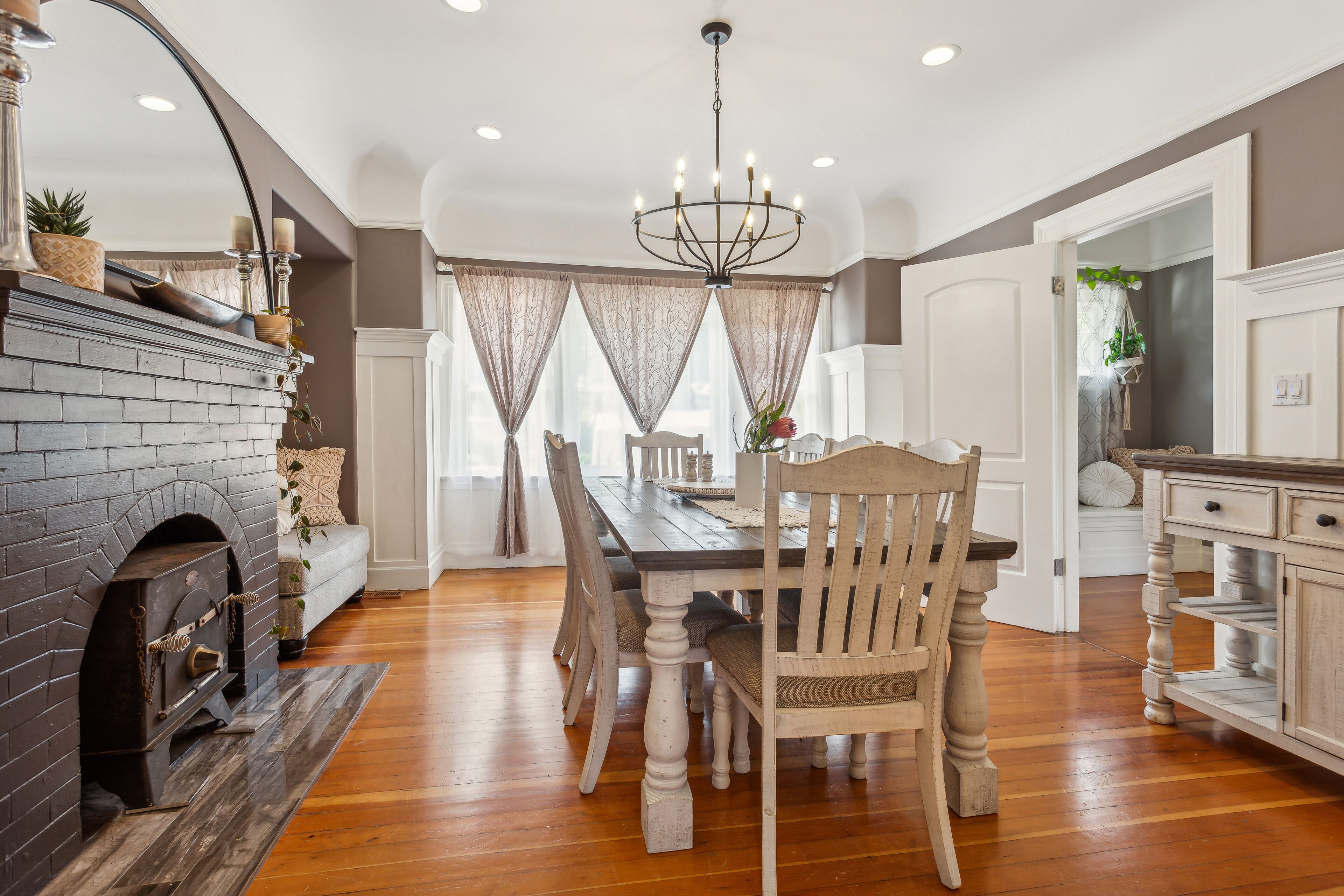 A dining area with a wooden table, chairs, a chandelier, and a fireplace.