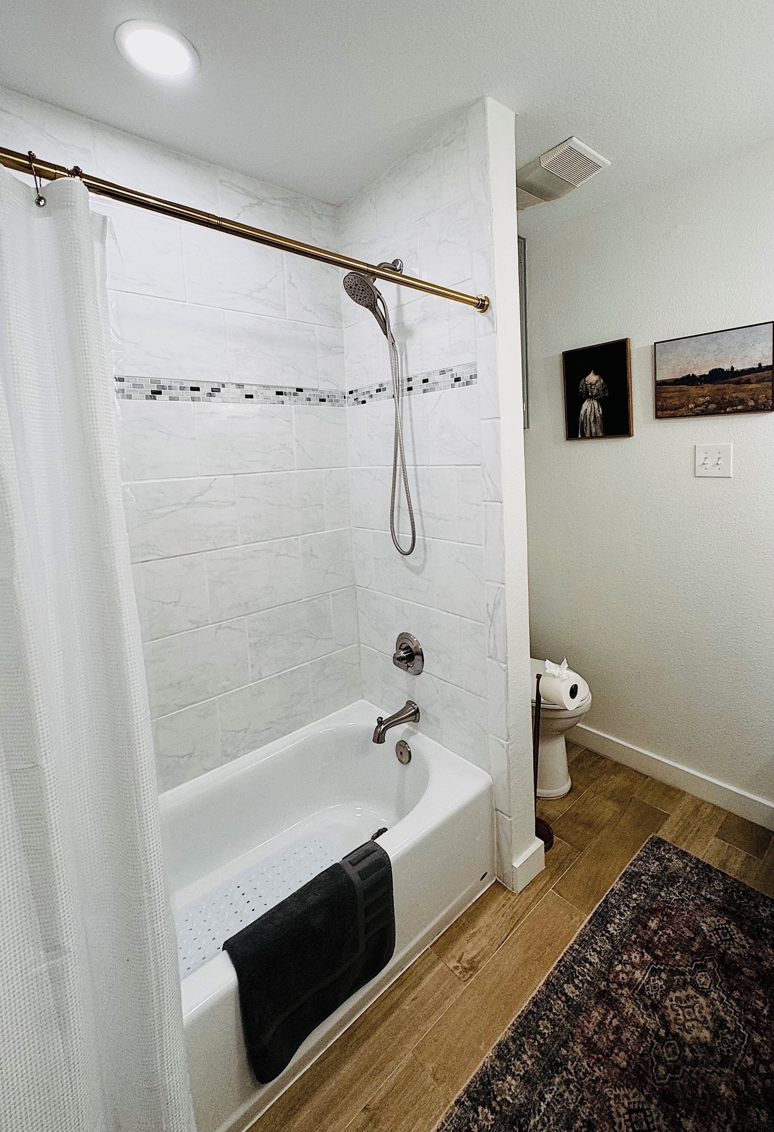 Een moderne badkamer met een witte badkuip, douche en betegelde muren.