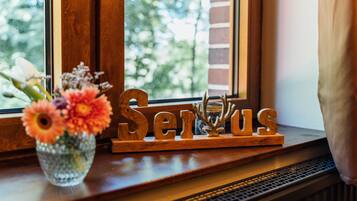 Ein Holzschild mit dem Wort 'Serious' auf einem Fensterbrett, neben einer Vase mit Blumen.