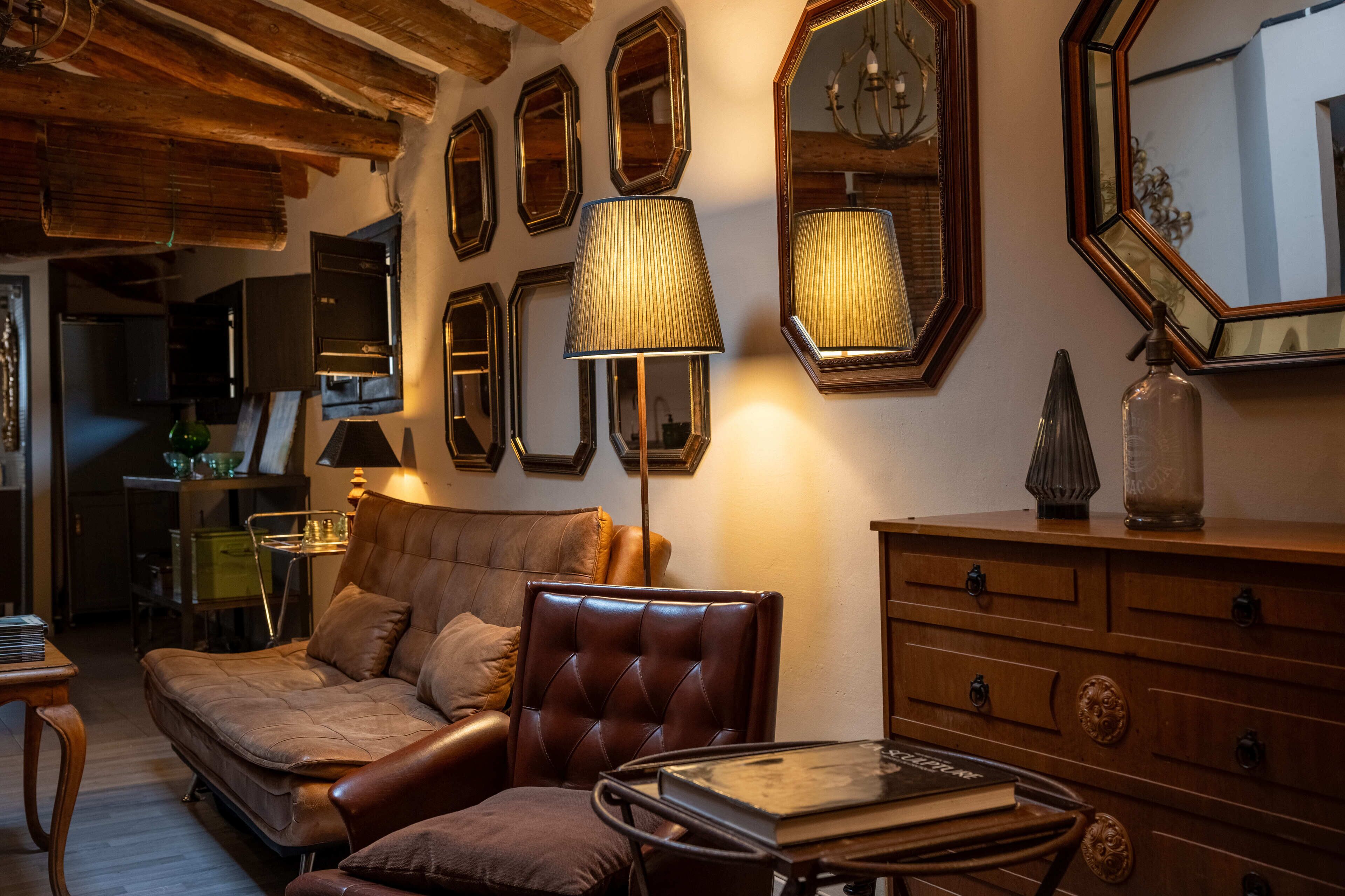 Een gezellige woonkamer met een leren bank, een glazen salontafel en een houten kast.