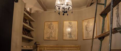 A bedroom with a large bed, a chandelier, and three framed sketches on the wall.