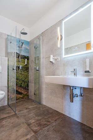 Features a wall-mounted mirror, sleek sink, and glass-enclosed shower with rainfall showerhead.