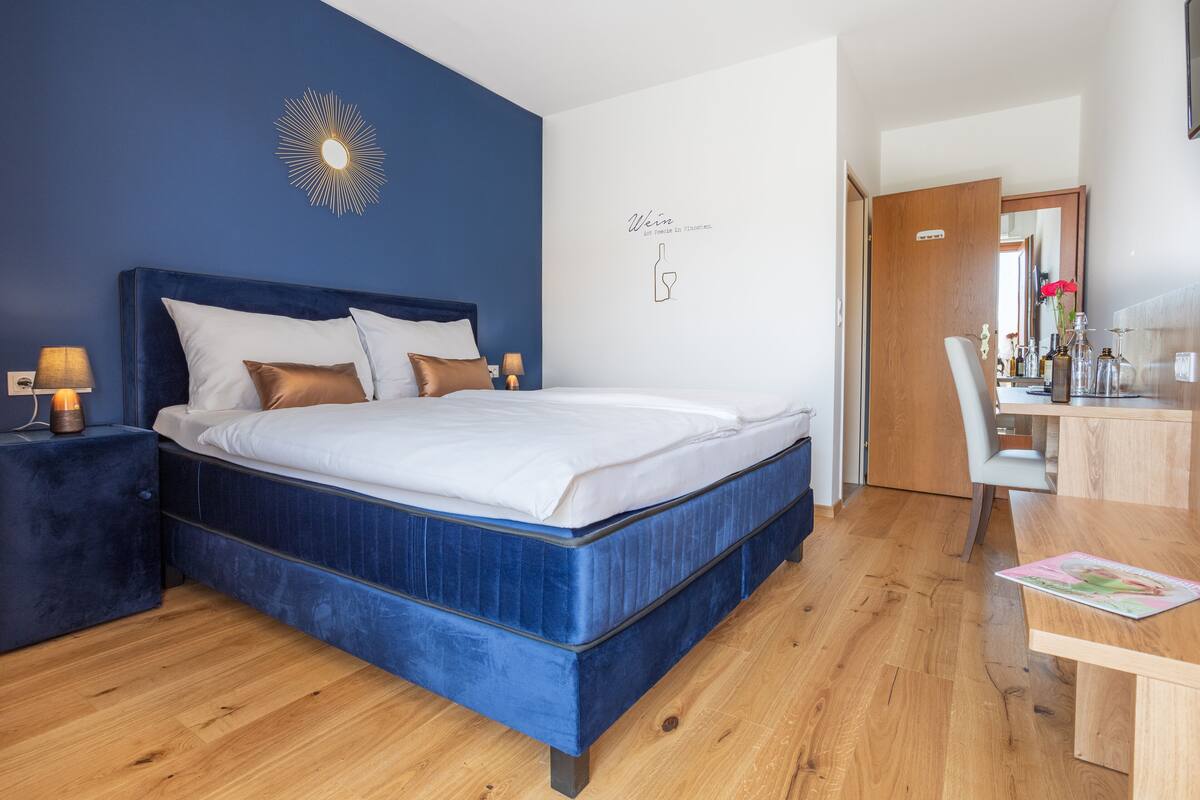 A bedroom with a large bed, a bedside table, a desk, and a chair.