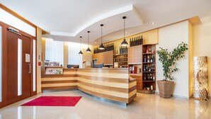 A modern reception area with a curved wooden counter, a red rug, and a wine display.