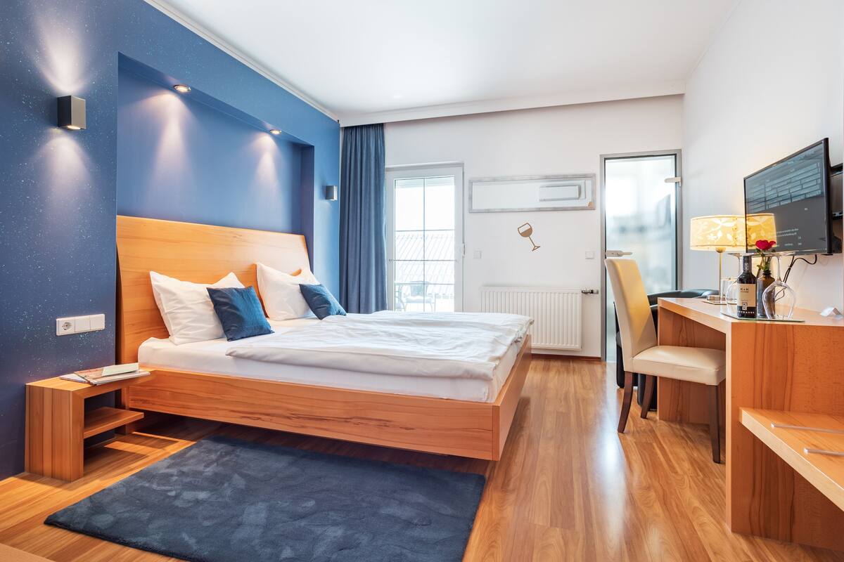 A modern hotel room with a wooden bed, a desk, and a chair.