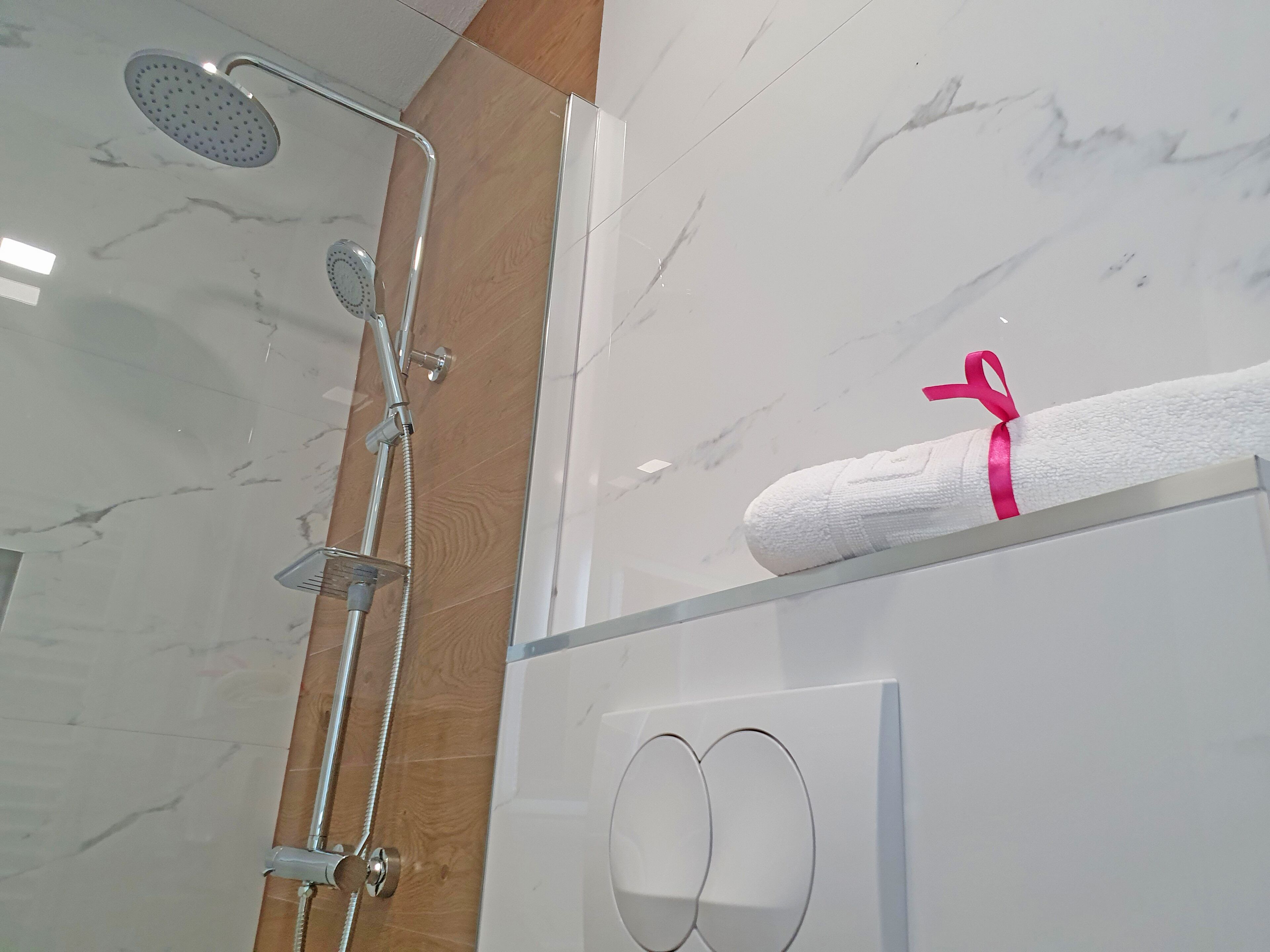 Une salle de bain moderne avec une douche à parois de verre, un panneau en bois et un porte-serviettes avec une serviette blanche.