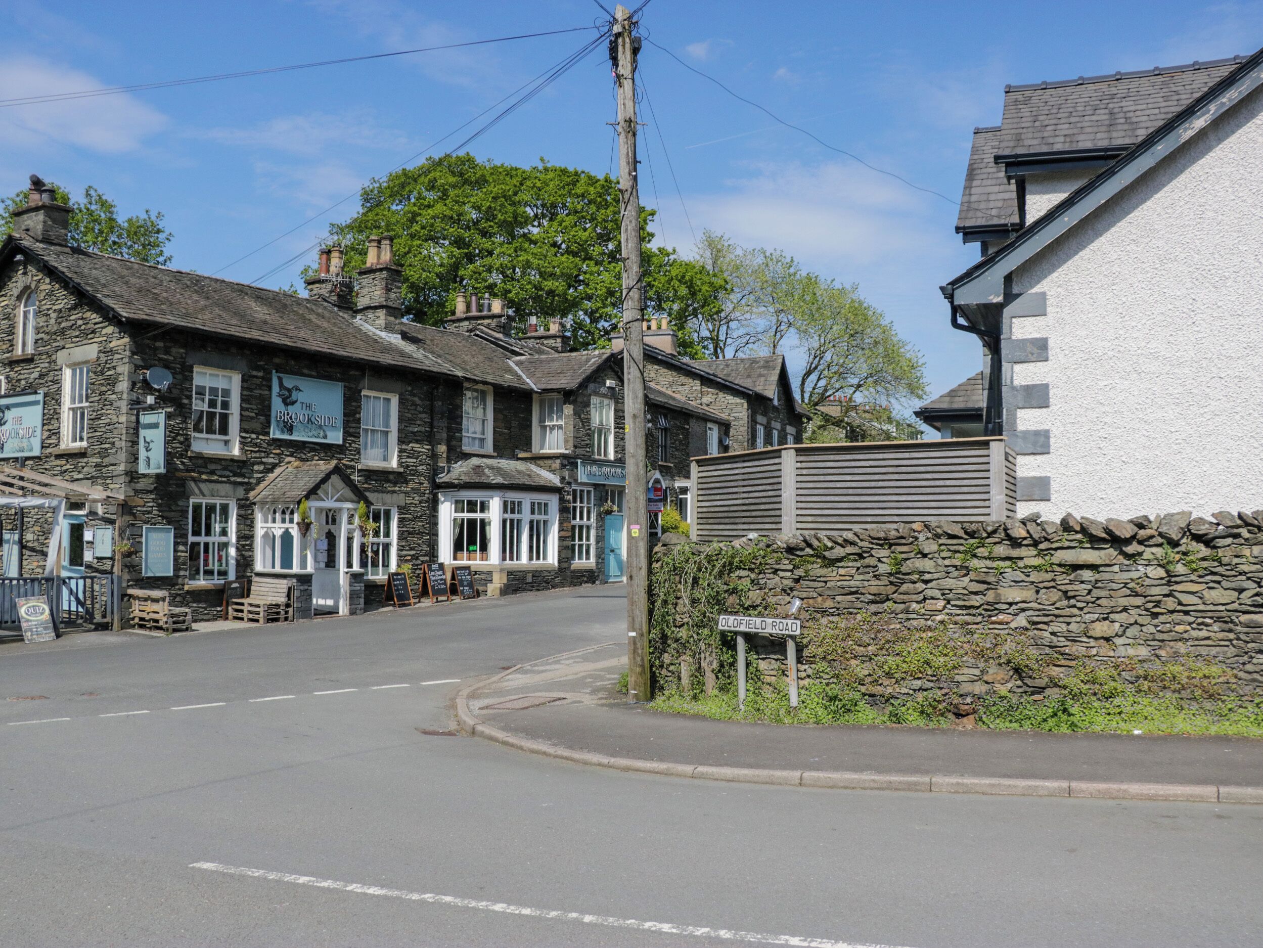 Vista de una calle con edificios tradicionales de piedra, incluyendo un pub llamado 'The Brookside'.