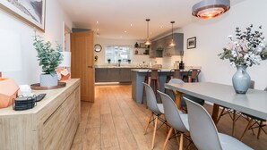 A modern kitchen with a central island, grey chairs, and a dining table. - Rose House (Windermere)