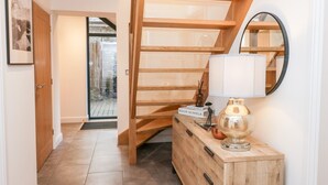 A wooden staircase with a glass railing, a wooden console table with a lamp, and a framed picture on the wall. - Rose House (Windermere)
