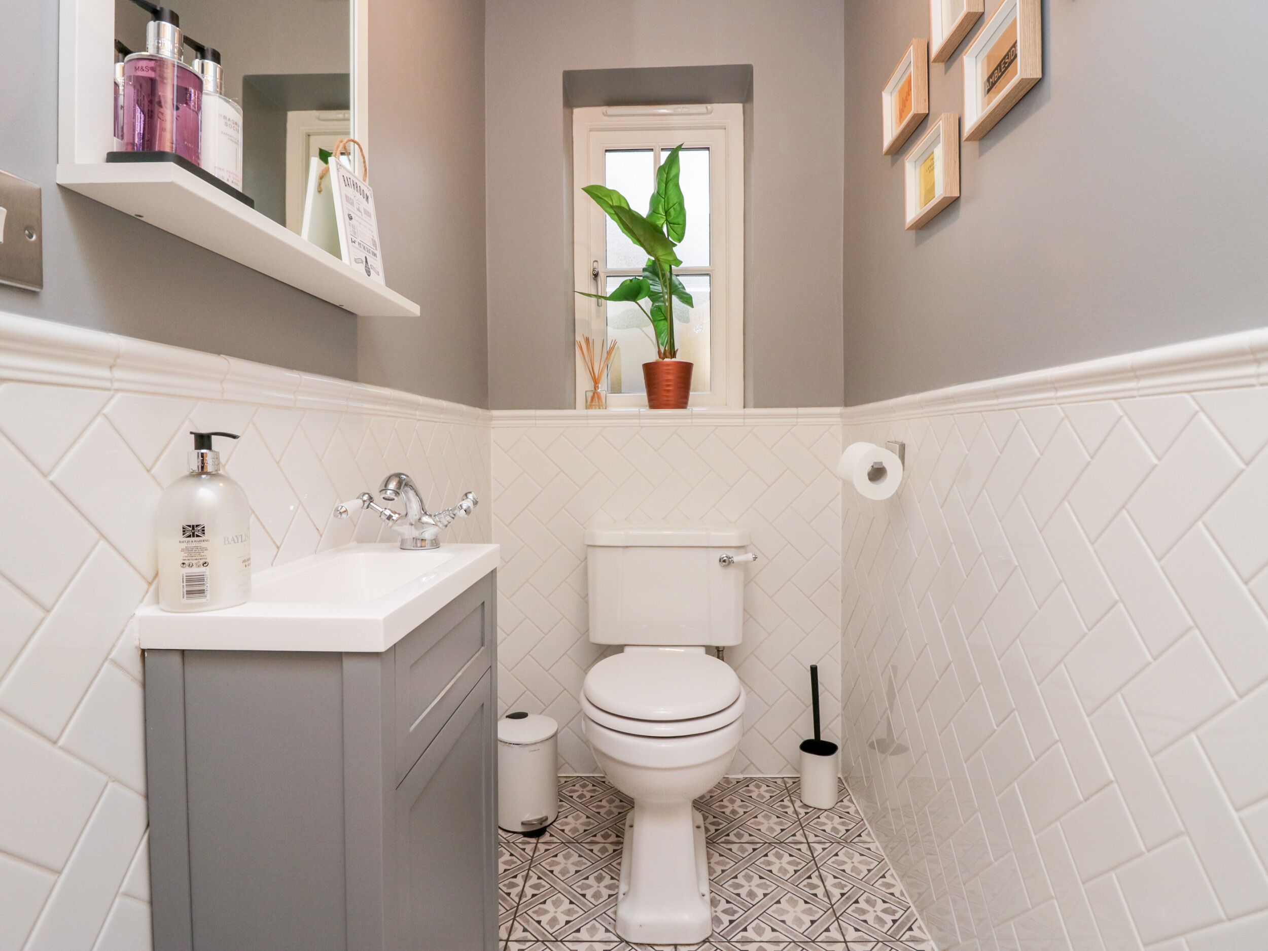 A bathroom with a toilet, sink, and a window with a plant.