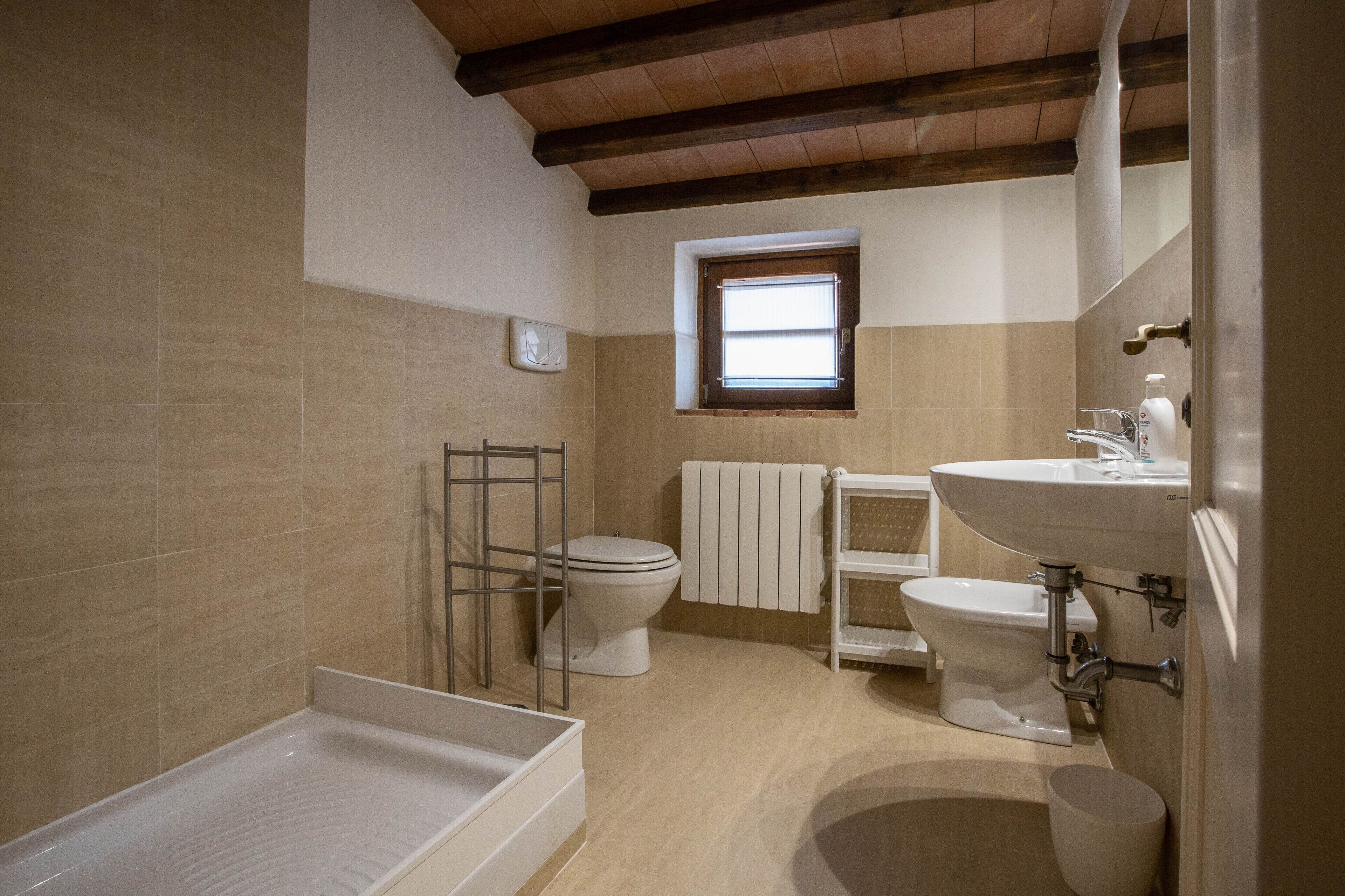 Une salle de bain avec une baignoire, deux toilettes, une fenêtre et un lavabo.