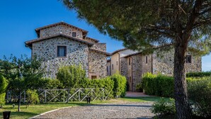A stone building with a paved driveway and a tree in the foreground. - Sweet country home (Montorgiali)