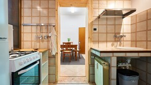 A compact kitchen with a stove, sink, and wooden cabinets. - Anastasio II apartment  (Rome)