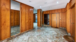 A hotel corridor with wooden paneling, marble flooring, and a mirror reflecting the space. - Anastasio II apartment  (Rome)