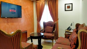A living room with a television displaying the Netflix logo, a sofa, a chair, and a small table. - Catherine Villa (Lagos)