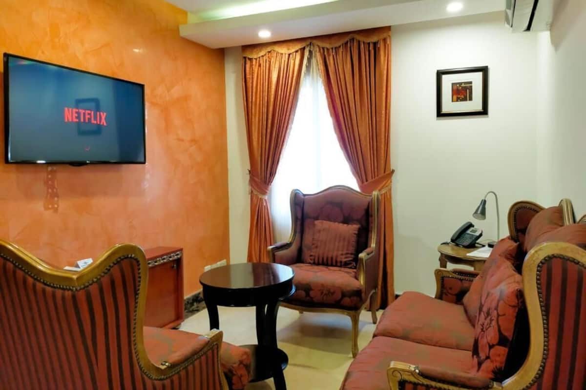 A living room with a television displaying the Netflix logo, a sofa, a chair, and a small table.