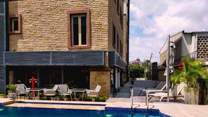 A swimming pool with lounge chairs and a red fire hydrant. - Catherine Villa (Lagos)