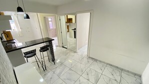 A modern kitchen with a black countertop, two bar stools, and a white cabinet.