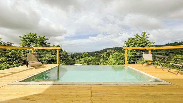 A rooftop pool with wooden decking, two wooden pergolas, and a view of a lush green landscape. - El Yunque Rainforest Villa, Pool, Toro Trail, 5-Acre Hacienda, Fruit Trees (Canóvanas)