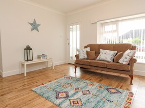A living room with a brown sofa, patterned cushions, a star decoration, a small table with a lantern, and a colorful rug. - 14 Berwick Road (Lytham St. Anne's)