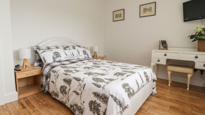 A neatly arranged bedroom with a bed, bedside tables, a desk, and a chair.