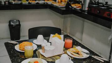 Um buffet de café da manhã com diversas opções de comida e bebidas.
