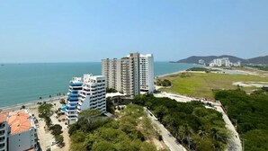 A coastal hotel with multiple high-rise buildings, a beach, and a clear view of the sea. - Suite deluxe with private Jacuzzi and ocean view. (Santa Marta)