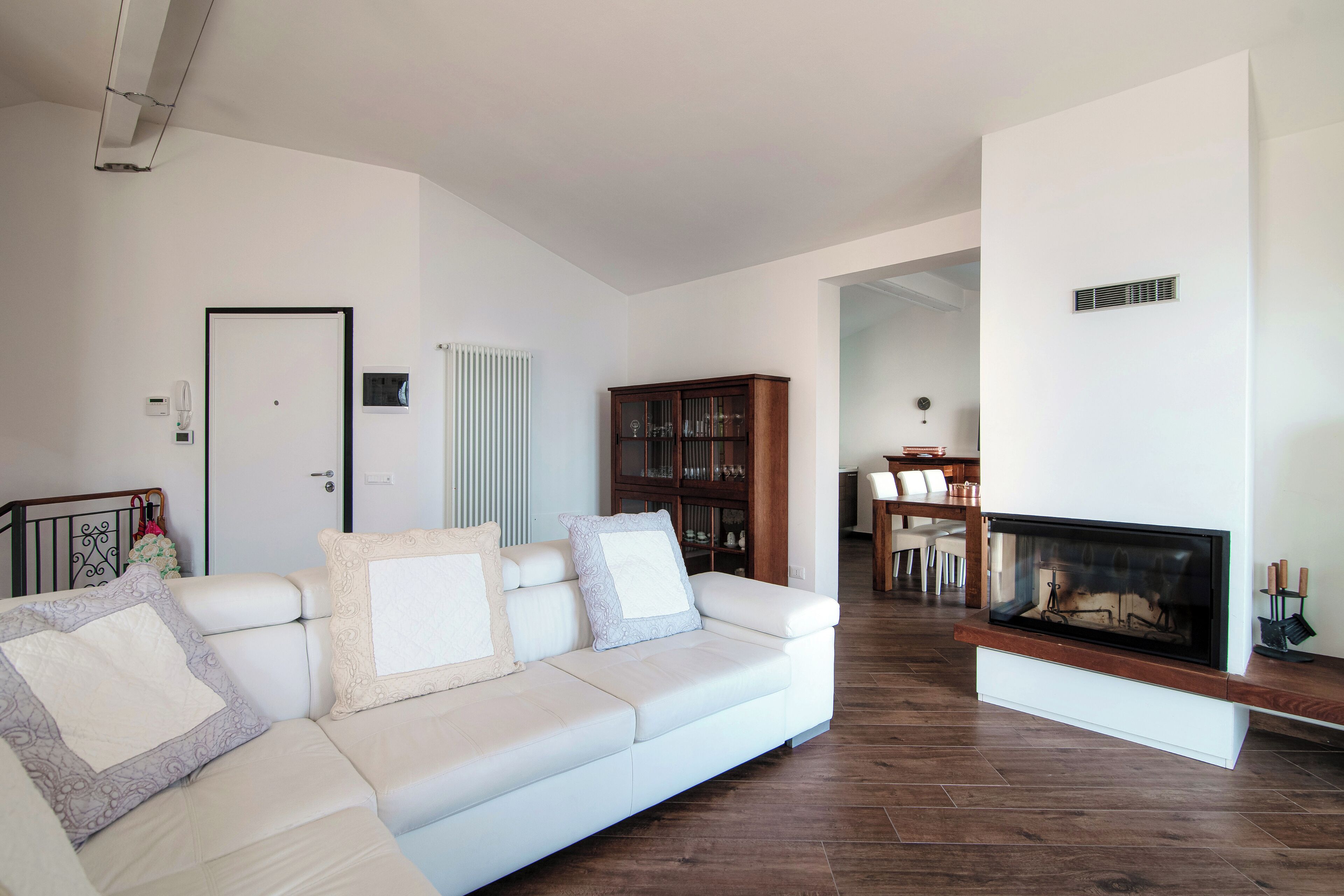 Un salon moderne avec un canapé blanc, une cheminée et un coin repas à l’arrière-plan.