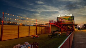 A restaurant with outdoor seating, a red staircase, and string lights.