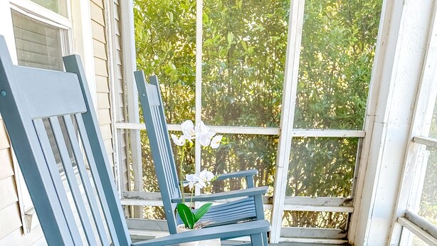 A porch with blue rocking chairs, a small table, and a potted plant. - Centrally Located Downtown, Full Kitchen, Patio (Laurel)