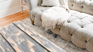 Un salon avec un canapé capitonné, un coussin à rayures, une lampe sur pied et un tapis au style rustique.