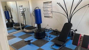 A gym with exercise equipment, a blue mat floor, and a wall-mounted poster. - THE PLACE (Las Vegas)