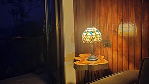 Una habitación moderna con una pared de madera, un vidrio y una mesa con lámpara.