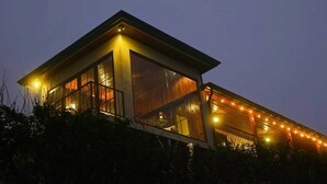 Un edificio moderno con amplios ventanales y techo plano, rodeado de vegetación.